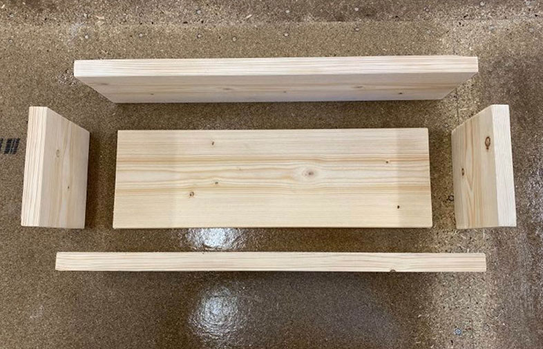 Fem ljusa furubrädor på betonggolv: två långa, ett brett mittstycke och två korta.