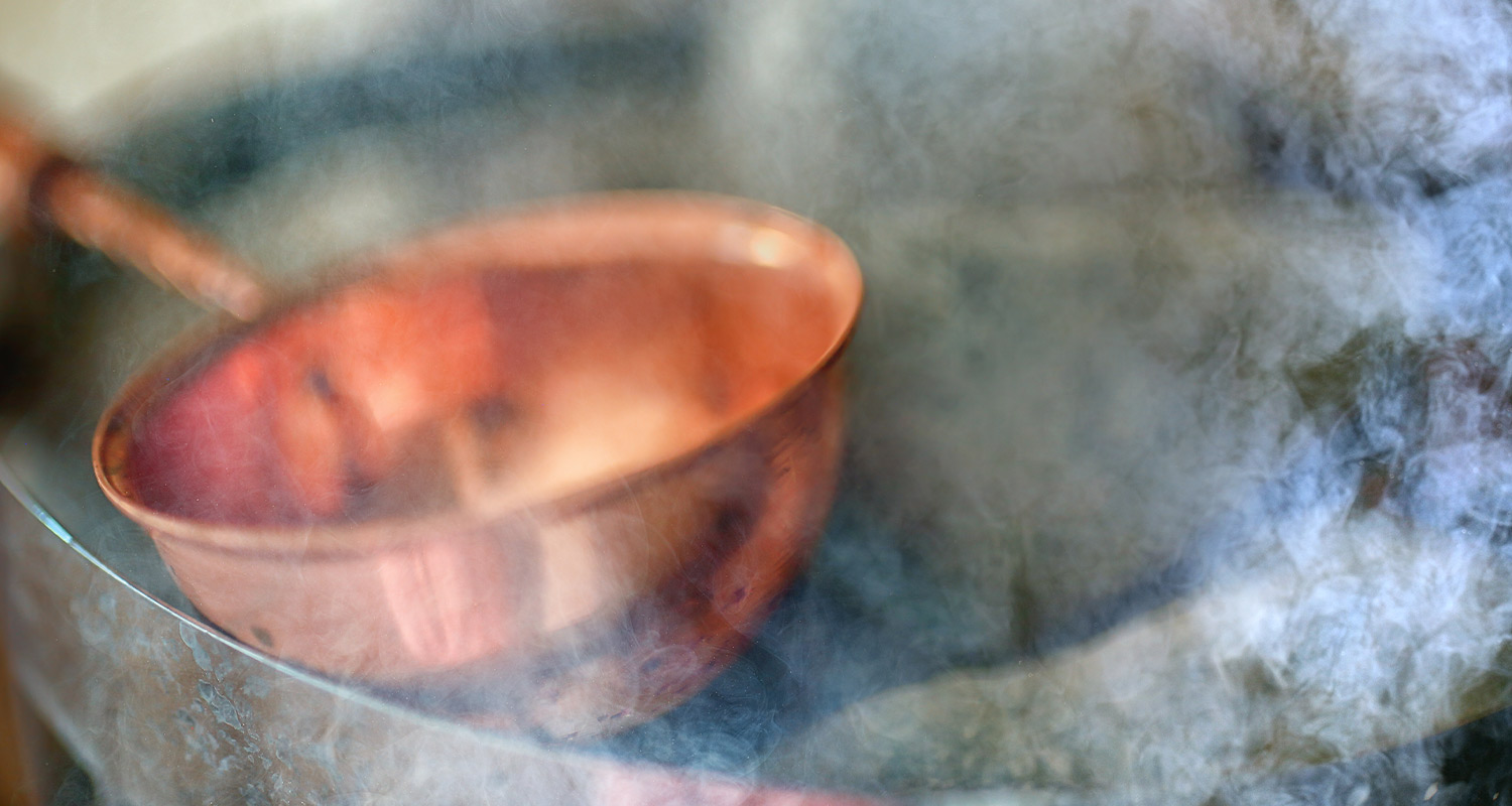 Skimrande koppargryta med handtag mot frostig, dimmig bakgrund.