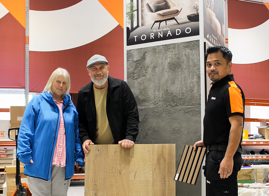 Tre personer i butik vid grå betongvägg och träprover, skylten "TORNADO" above.