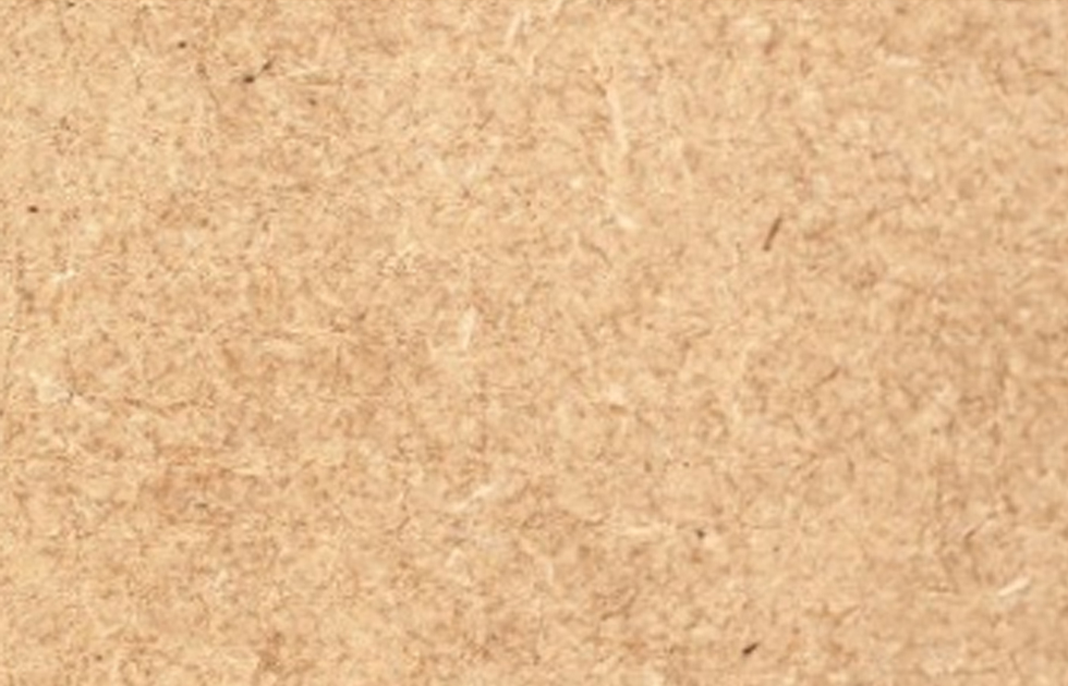 Närbild av ljusbrun pappers- eller kartongyta med synliga fibrer.