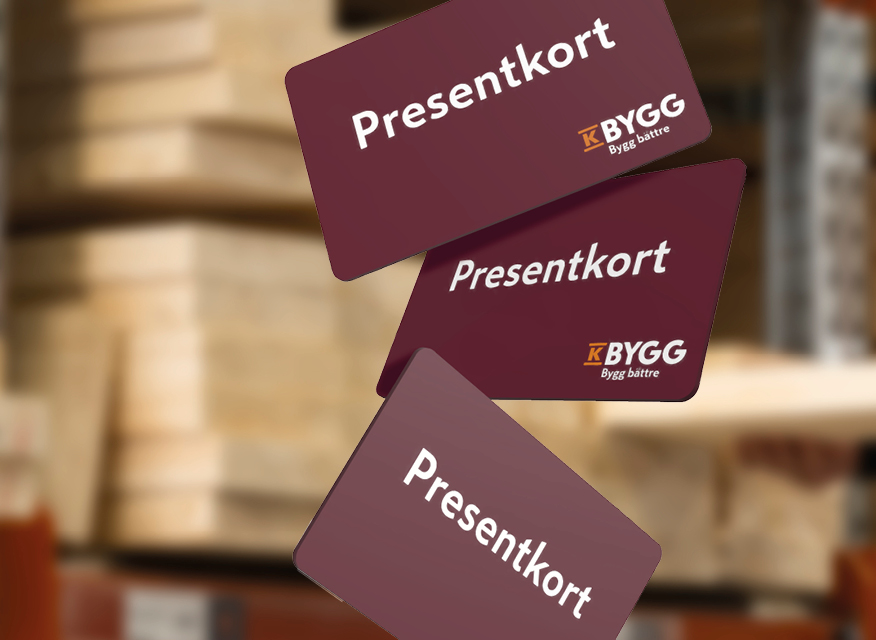 Två K-Bygg-presentkort i vinrött, vitt och orange på ljusgrå bakgrund bredvid inslaget paket