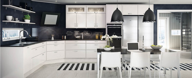 Modern svartvitt kök med vita skåp, svart griffeltavla, köksö, pendellampor och matplats.