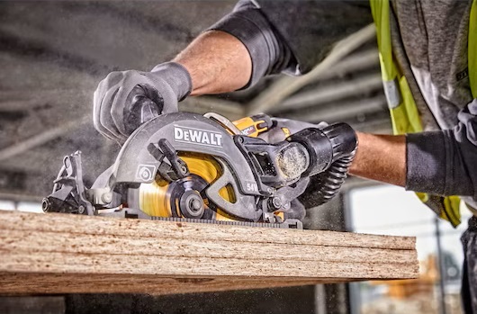 Närbild på snickare i gul varselväst som sågar spånskiva med grå-gul DeWalt cirkelsåg.
