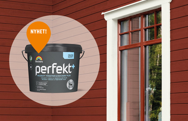 Svart Beckers ’perfekt+’ färghink med orange ’NYHET!’-skylt mot röd träfasad och vitt fönster.