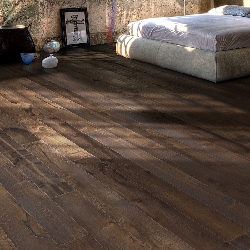 Mörkt brunt trägolv i solstrimmor i industriellt sovrum med låg vit säng, betongvägg och konst