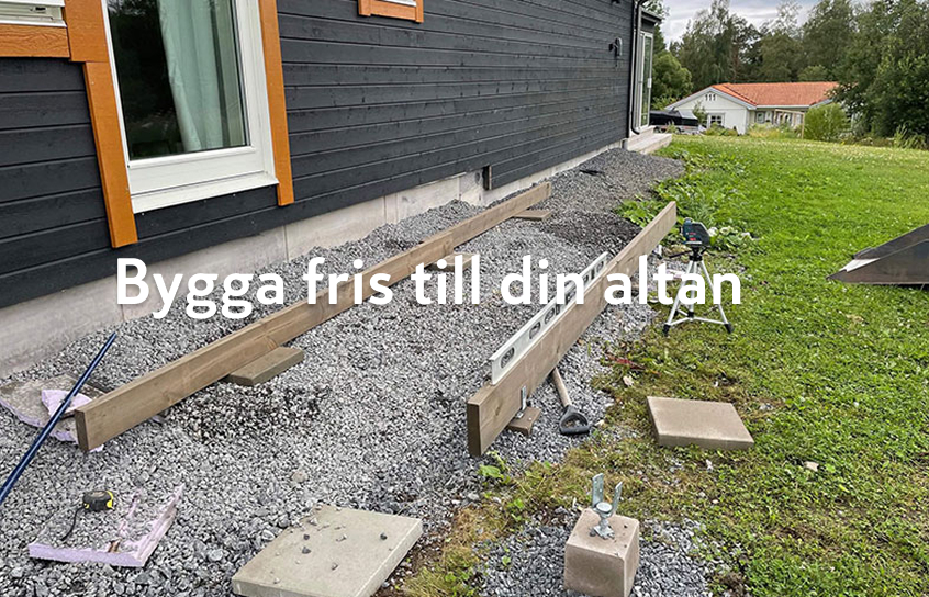 Svart hus med orange fönsterfoder, trallgrund på grus med träreglar, vattenpass och grön gräsmatta.