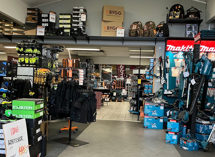 Byggvaruhusinteriör med arbetskläder, gula skyddshandskar och blå Makita-verktyg