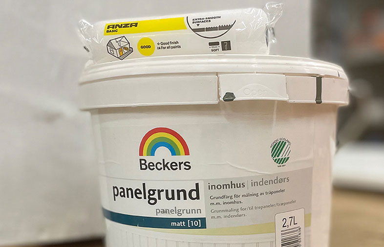Vit 2,7 L Beckers inomhus-panelgrundburk med regnbågslogga och vit målarroller i plast.