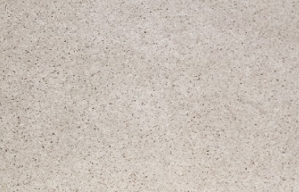 Närbild på en beige, kornig yta med små mörka prickar.