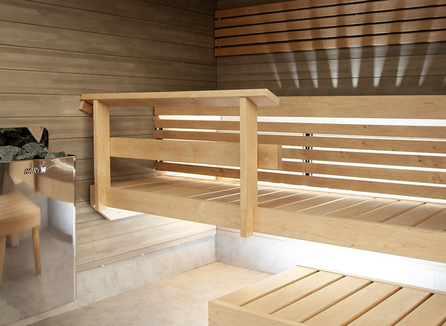Ljust träinteriör i modern bastu med flera våningsbänkar, dold LED-belysning och rostfri värmekamin