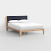 A modern wooden bed frame with angled legs, a dark upholstered headboard, white bedding, and two pillows, set against a plain white background.