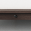 Close-up view of a dark wooden bed frame with a visible black metal bolt in the center. The floor is gray, and a white surface is visible above the frame.