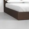 A close-up of a bed with a dark wooden frame and white bedding, positioned on a light gray floor. The focus is on the corner of the bed and the crisp, clean lines of the design.