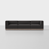 A modern, dark gray three-seat sofa with clean lines and square arms, set against a plain white background. The sofa has a low profile and sits on a light-colored wooden base.