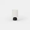 Small cylindrical table lamp with a dark base and a light-colored drum shade.