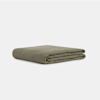 A neatly folded olive green blanket is placed on a plain, light gray background.