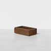 A rectangular wooden box with smooth sides and an open top, placed on a light gray surface against a plain white background.