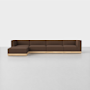 A modern sectional sofa with brown upholstery and a light wooden base, featuring a left-facing chaise and clean, minimalist design, set in a bright room with a white floor and background.