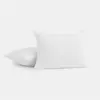 Two white, rectangular pillows with subtle textured patterns are placed on a plain white background. One pillow stands upright, while the other lies flat behind it.