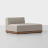 A modern, minimalist sectional chaise lounge with light beige upholstery and a low wooden base, set against a plain white background. The chaise has a single backrest on the left side.