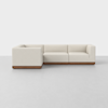 A modern, L-shaped sectional sofa with off-white upholstery and a wooden base, set against a plain white background.