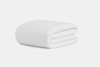 A neatly folded, plain white blanket is placed on a white surface against a plain white background.