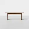 A minimalist wooden table with a rectangular top and four straight legs, set against a plain white background.