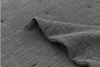 A close-up of a textured, dark gray fabric with a crinkled, grid-like pattern and a gentle fold in the center.