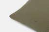 Close-up of a green pillow with a textured, grid-like fabric pattern against a plain white background.