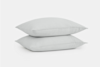 Two plain white pillows stacked neatly on top of each other against a white background.