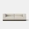 A modern, minimalist beige sofa with straight lines and a low backrest, featuring a dark wooden base, set against a plain white background.