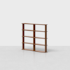 A modern wooden bookshelf with three vertical dividers and four shelves, standing empty against a plain white background on a light gray floor.
