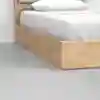 A close-up of a modern wooden bed frame with white bedding and pillow, positioned on a smooth, light gray floor.