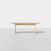 A minimalist wooden bench with a light finish, featuring a flat top and simple, straight legs, set against a plain white background.