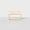 A minimalist wooden table with a rectangular top floating slightly above a matching rectangular base, set against a plain white background on a light gray floor.