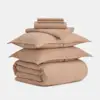 A neatly stacked set of tan-colored bedding, including two pillowcases, a duvet cover, a fitted sheet, and a flat sheet, arranged against a plain white background.