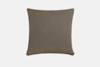 A square, taupe-colored fabric pillow with smooth texture, shown against a plain white background. A small black tag is visible on the lower right edge.