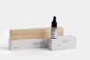 A dropper bottle labeled Deep Forest Essential Oil Dropper is displayed on top of a white box, next to a rectangular wooden box labeled From Soil to Form Diffuser. Both boxes have minimalist designs.