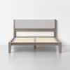 A modern wooden bed frame with light gray upholstered headboard, slatted base, and minimalist design, set against a plain white wall and gray floor.