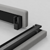 Two upholstered bed frame sections in grey fabric are shown on a white surface, with exposed black metal brackets and rails positioned for assembly. The parts appear ready to be joined together.
