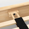 Close-up of a wooden bed frame joint with a black fastener and a black fabric strap securing two wooden slats together. The wood has a light, natural finish.