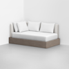A modern daybed with a light wood base, white mattress, and four white pillows, positioned against a white wall in a minimalist room with a light gray floor.
