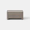 A rectangular, light brown wooden storage chest with simple, clean lines sits on a smooth, light gray floor against a plain white background.