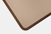 Close-up of the corner of a rectangular object with a smooth, beige surface, surrounded by a dark brown, rounded border, placed against a white background.