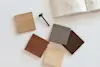 Four wood samples in different shades are arranged on a white surface near a black screw and an open sketchbook with technical drawings.