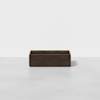 A rectangular, dark wood storage box with an open top is placed on a light gray floor against a plain white background.