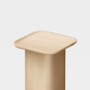 A wooden pedestal with a cylindrical base and a square, slightly rounded top against a plain white background.