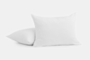 Two white pillows with subtle textured patterns, one standing upright and the other lying flat, set against a plain white background.