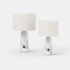 Two modern table lamps with cylindrical white fabric shades and marble-patterned bases, one taller than the other, set against a plain white background.