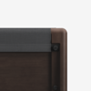 Close-up of a dark wood bed frame corner with rounded edges and a dark gray upholstered headboard, against a plain white background.